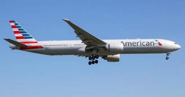 Білий Boeing 777 American Airlines летить у ясному блакитному небі з випущеним шасі