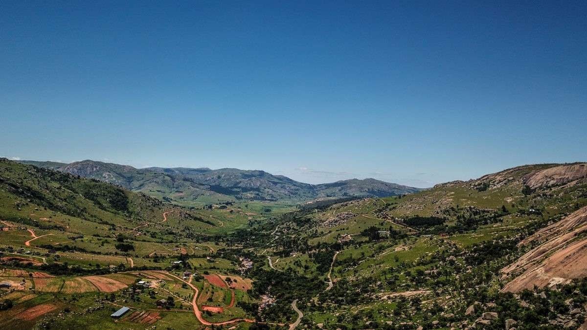 Панорама долини з горами, зеленими полями та селищем вдалині